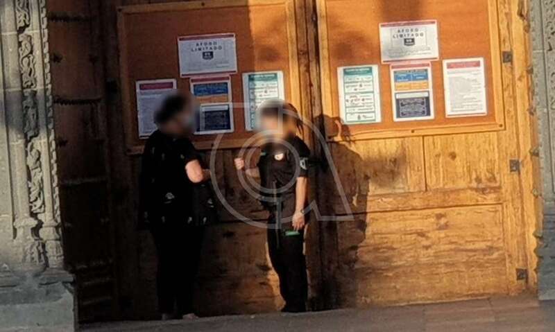 La vigilante de seguridad, en la puerta del templo, charla con una feligrés/TA.